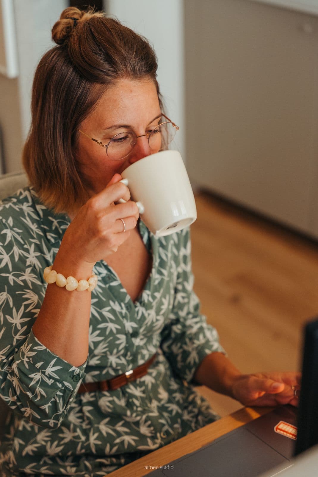 Une coworkeuse boit un café à son bureau